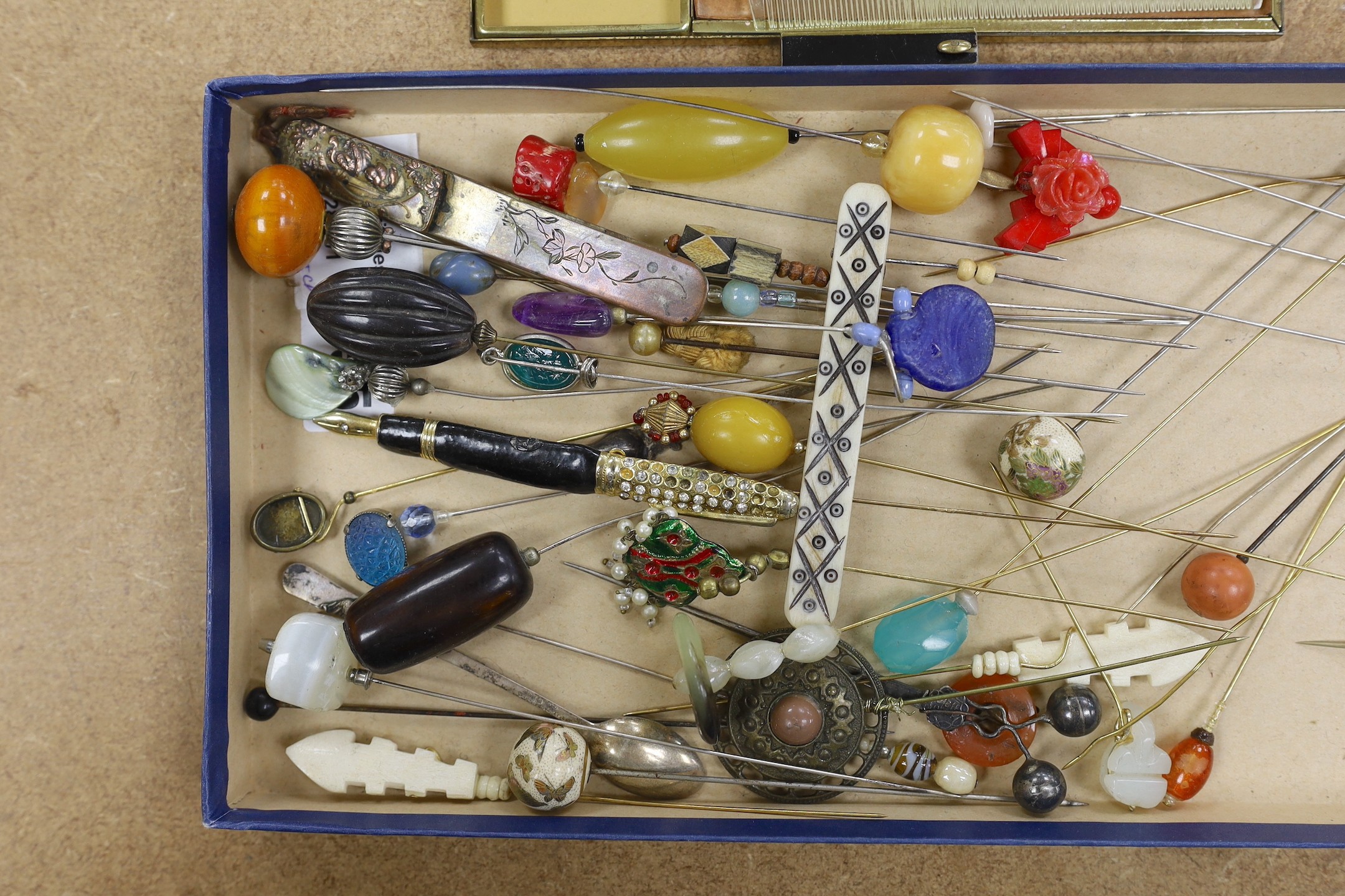 A collection of hat pins and a large enamel compact